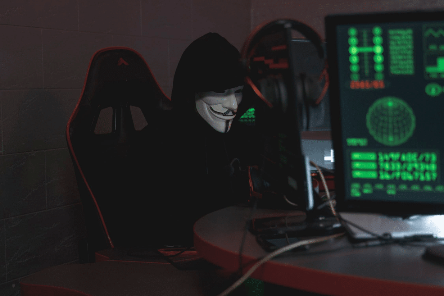 An image of a person using a computer while wearing a Vendetta mask